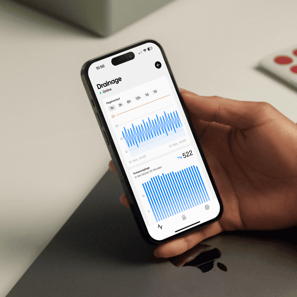 Eine Hand über einem Tisch mit einem iPhone in der Hand. Das iPhone hat die Drainbee App geöffnet.